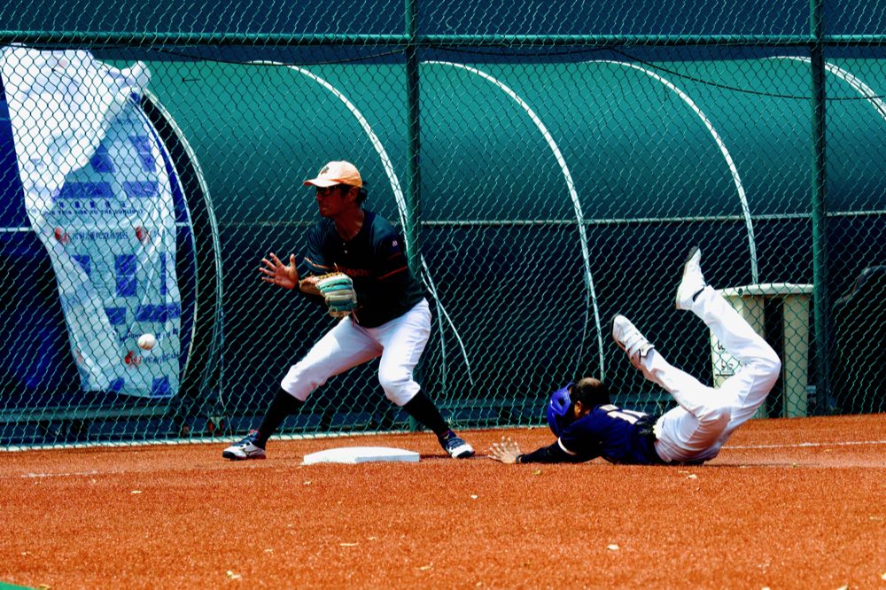 Infielder waits on the throw as a Tusker dives back into the bag